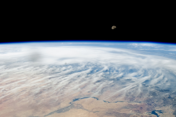 A photo taken by NASA from above the Middle East captures the Moon peeking over Earth’s atmosphere.