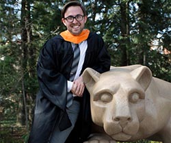 a person wearing masters degree commencement robe leans against a statue of the Nittany Lion