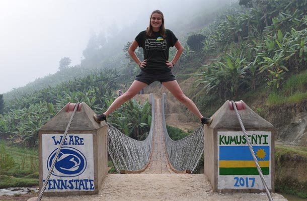 college student poses on footbridge in Rwanda