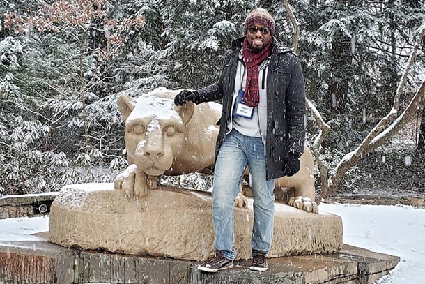 A man stands at the Nittany Lion Shrine during a snow storm