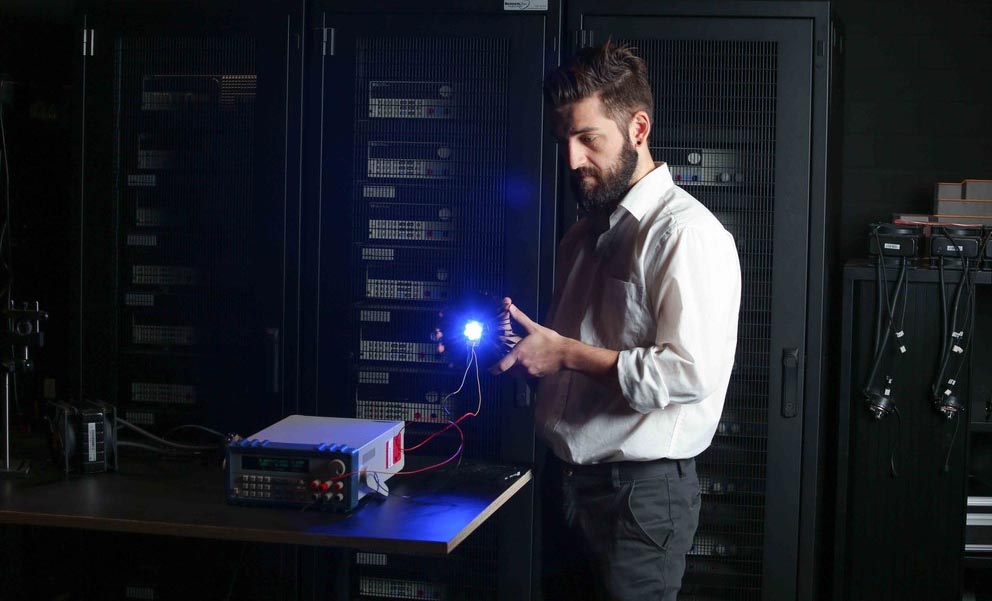 A man holds a lighting device in a dark room