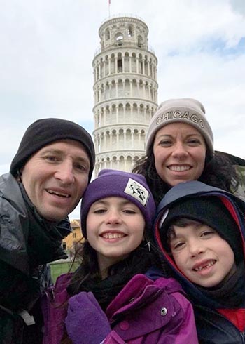 a family standing in front of the tower of pisa in italy
