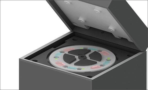 An illustration of a device that resembles a gray box with the lid lifted. On the top of the box under the lifted lid is a disk-like object.