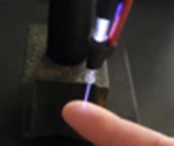 A laser-like jet is projected onto the underside of an index finger.