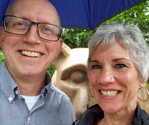 a man and a woman pose for a selfie with the Penn State lion statue in the background