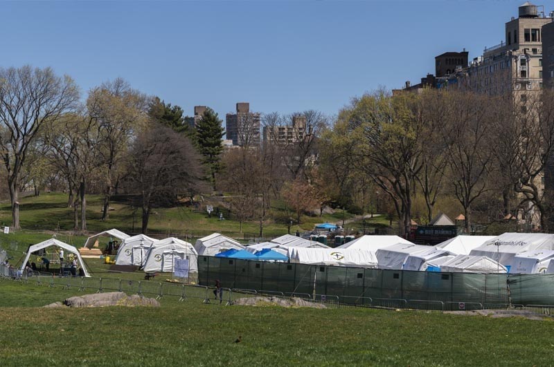 Tents set up in a green field with cityscape in the background