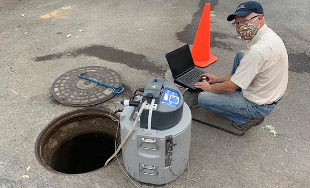 a man taking wastewater samples from a manhole
