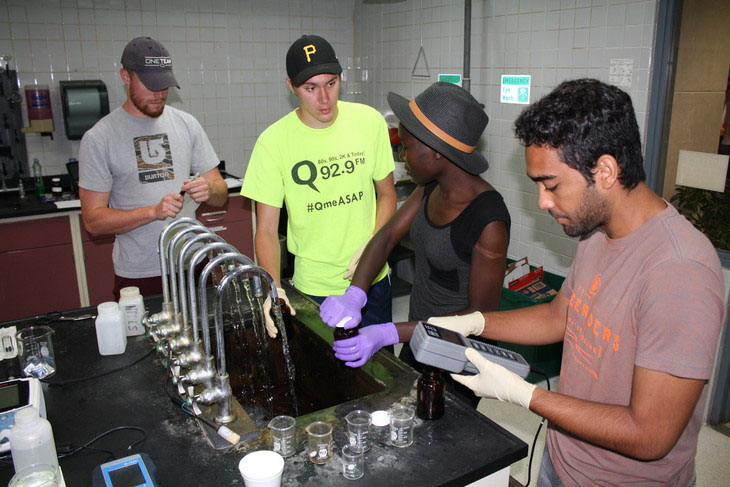 Four individuals gather around sink while conducting experiments.