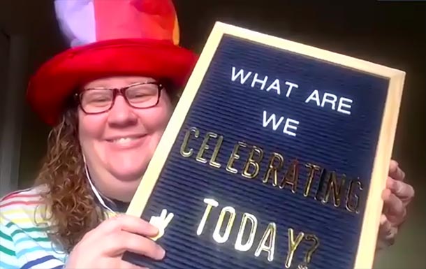 a woman wearing a funny hat holds of a sign that reads what are we celebrating today