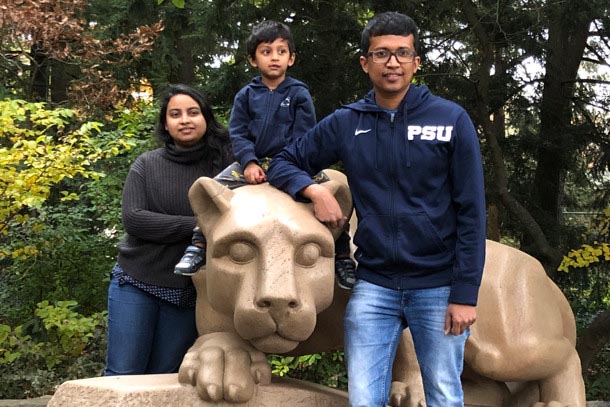 A man, woman, and boy pose for a picture beside a mountain lion statue.