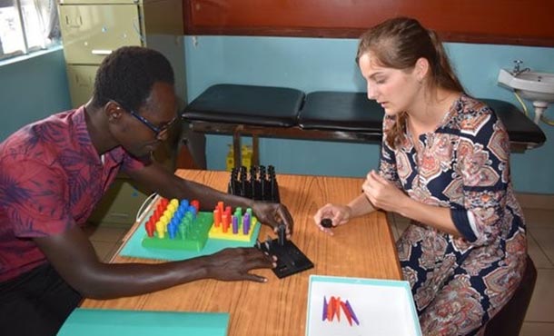 a female undergraduate student and a Kenyan man work with a 3 D printed peg board