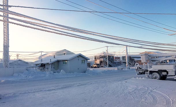 a winter street scene showing snow-covered buildings, roads, and utility lines