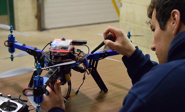 A student makes an adjustment to a drone.