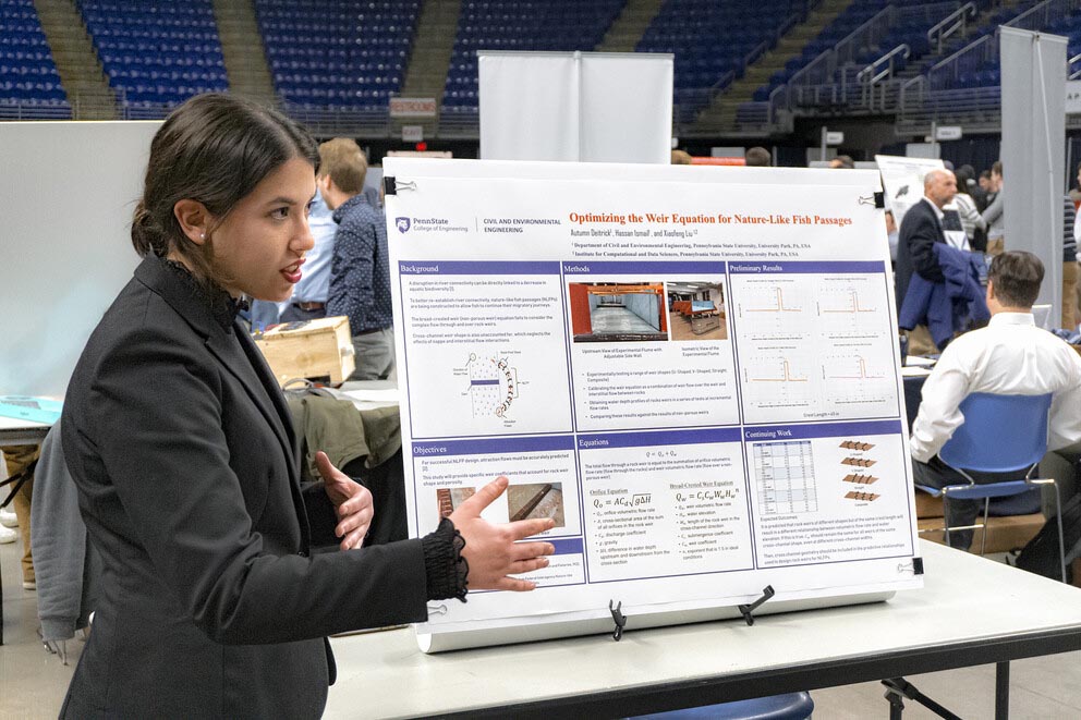 a woman presents her research poster at an event