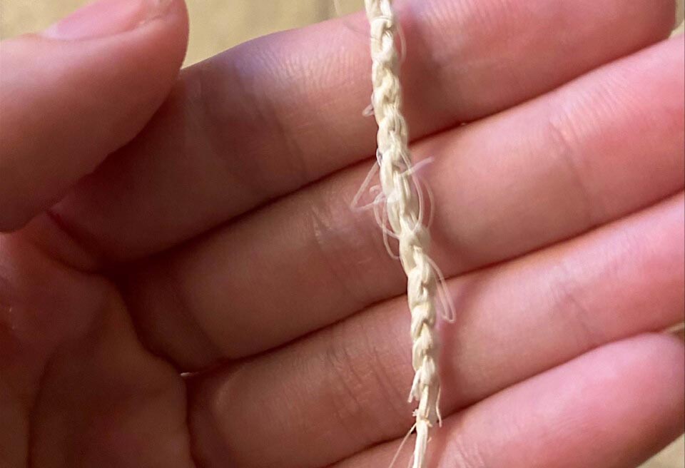A chain made of white fiber rests in the palm of a hand