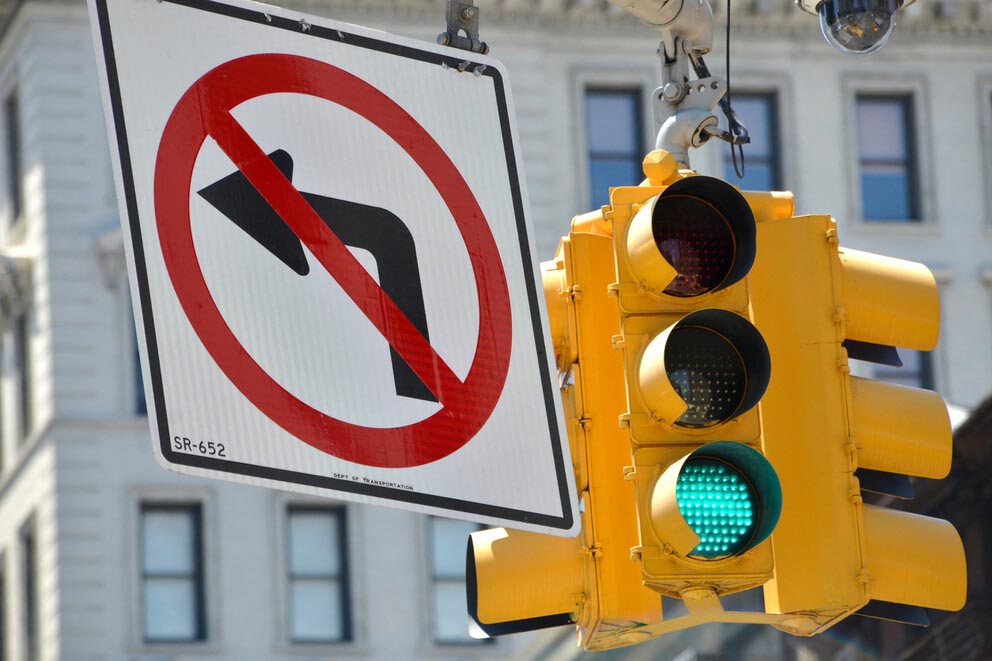 a sign that reads no left turn hangs next to a traffic signal at a city intersection