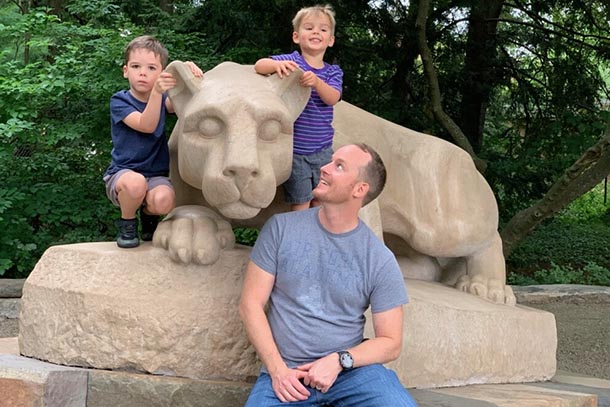 a man and his two sons pose with the statue of the nittany lion mascot