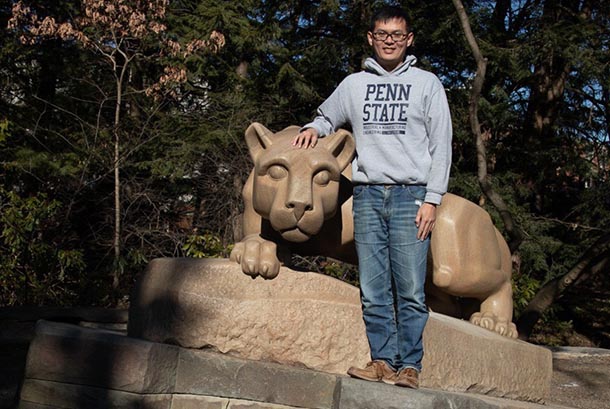 a man stands next to a statue of the penn state nittany lion mascot