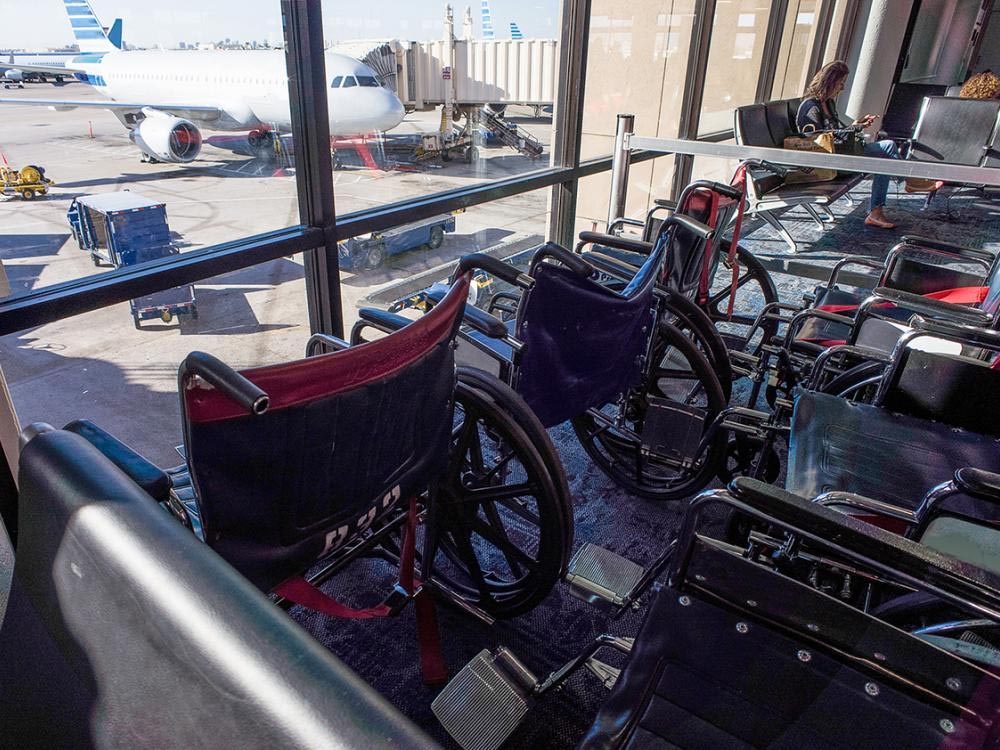 empty wheelchairs lined up at the gate area inside an airport terminal