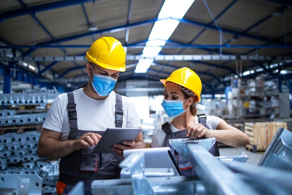 Two workers wearing face masks in a manufacturing/factory setting