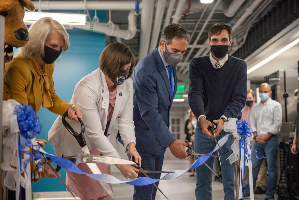 Four people cut a ribbon in the M E Knowledge Lab.