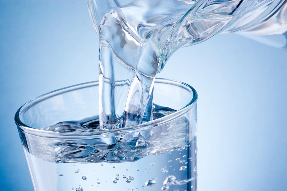 clear water is poured from a pitcher into a glass