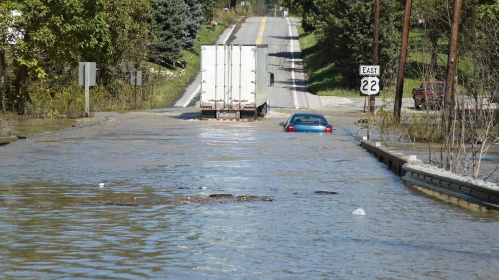 partially submerged vehicles abandoned in a flooded rural roadway