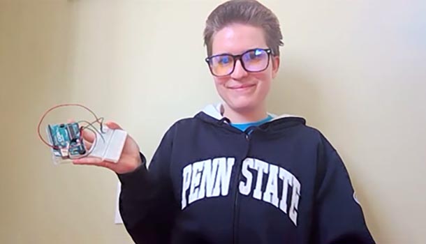 A female engineering student holds up a test kit and smiles.