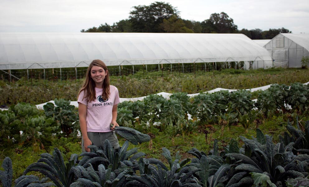 a woman stands in a vegetable garden