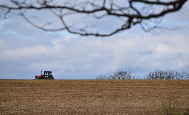 a tractor moves across a sloped field