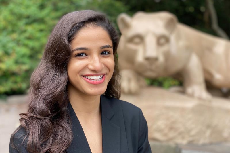 headshot of a woman with the head of the nittany lion statue in the background