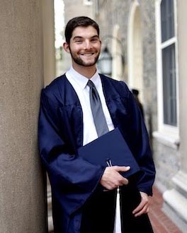 a man wearing a cap and gown stands outside a building