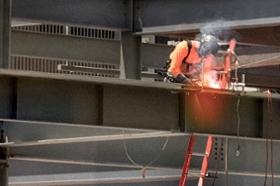close up shot of construction worker welding steel on the new west campus building