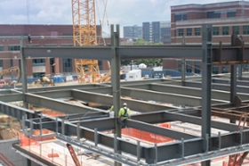 wide shot view of construction workers working to install steel beams for the new west campus buildings