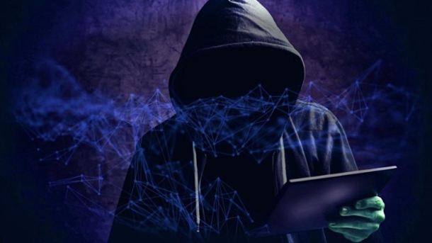 faceless computer hacker in oversized black sweatshirt holding a computer