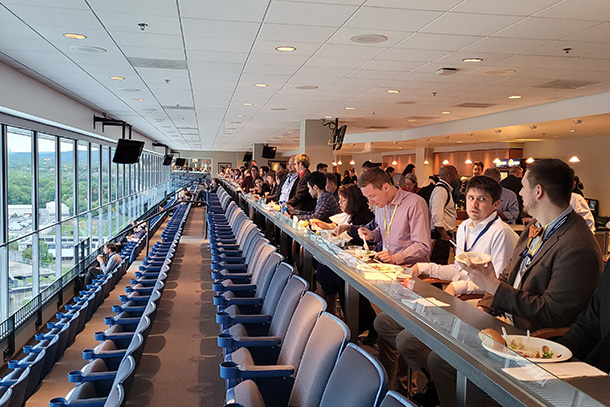 large group of people eat lunch in stadium box seats