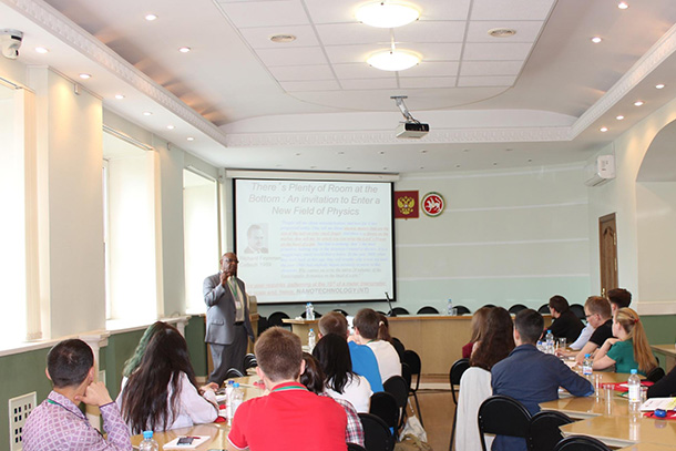 Person standing next to projection screen in classroom presents lesson to college students