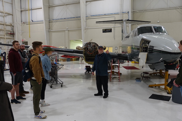 students listening to an instructor provide information about the aircraft that is in the room