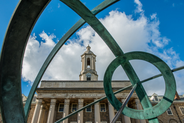 Penn State's historic Old Main building and bell tower are seen on a partly cloudy day.