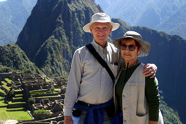 Ron Danner and his wife wearing sun hats pose on Machu Picchu mountaintop in Peru