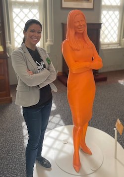 person standing beside an orange 3D-printed life-size statue of themself