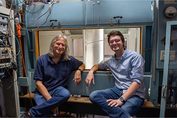 Two people in blue jeans and blue shirts smile at the camera.