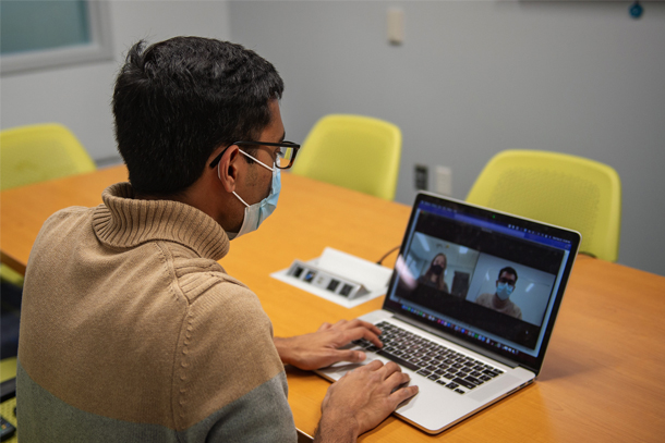 Researcher looking at a computer screen where a virtual meeting is taking place.
