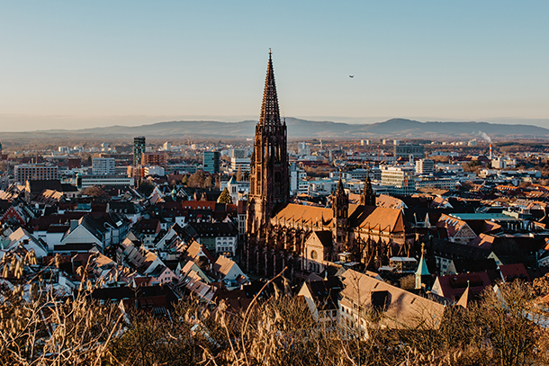 A cityscape depicting Freiburg, Germany featuring a large cathedral on a sunny winter's day.