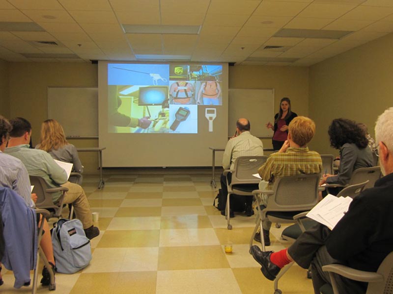 Person stands at the front of a room and presents to an audience