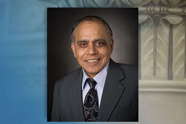 headshot of a man in a suit and tie on a blue and gray background