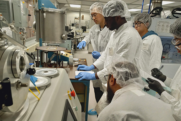 five people wearing safety wear in manufacturing laboratory