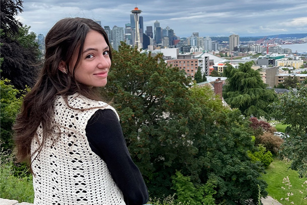 An individual look over her right shoulder with a city in the background