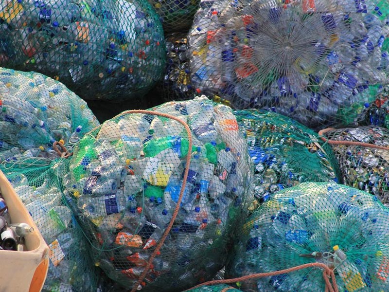 piles of clear plastic trash bags filled with multi-colored empty plastic bottles