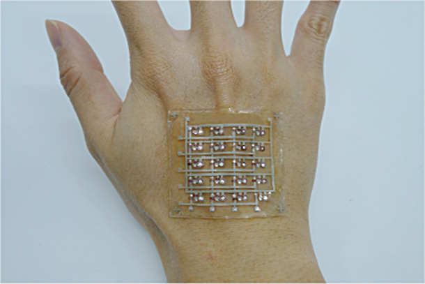 square of rubber skin with sensory transmitters on the back of a human hand